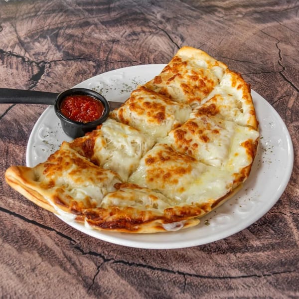 Cheesy garlic bread, cut into triangles, served with a side of marinara sauce on a white plate.