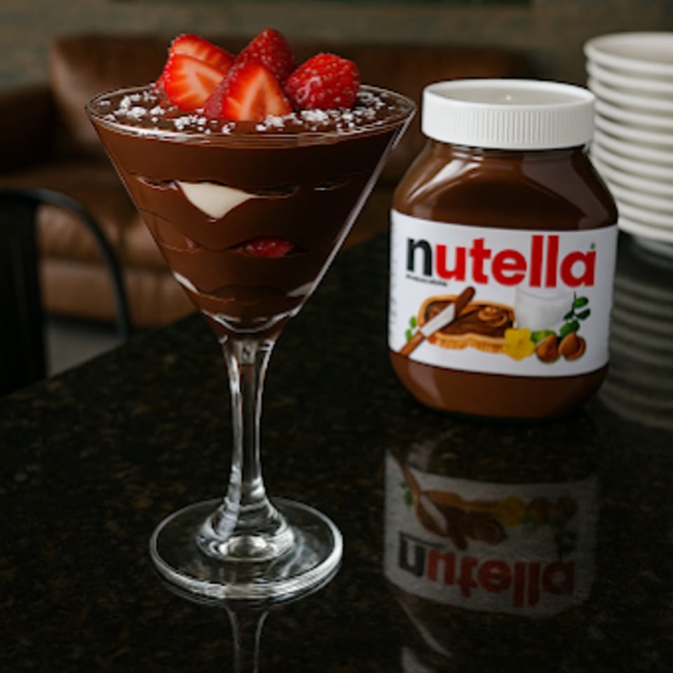 Nutella dessert in a martini glass with strawberries and a jar of Nutella.