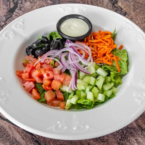 A fresh J&J PIZZA RESTAURANT side salad with lettuce, tomatoes, cucumbers, olives, onions, carrots, and dressing.